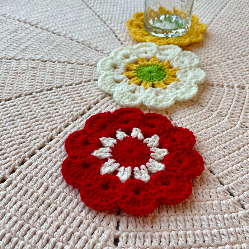 Several deep-red crochet pieces arranged together on a warm gray background